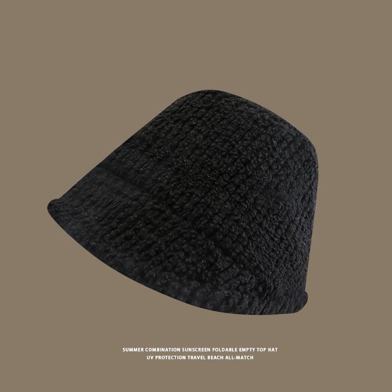 Black plain textured bucket hat displayed at angle against taupe background, part of UV protection travel collection
