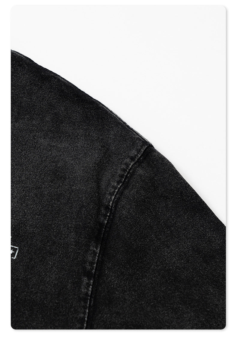 Close-up of black t-shirt sleeve hem stitching detail against white background.