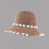 Brown woven straw hat with a wide brim, decorated with white floral embroidery along the edge and band, displayed on a gray background.