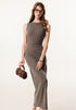 Female model in a brown ribbed sleeveless bodycon maxi dress, accessorized with a brown handbag and tortoise-shell glasses.