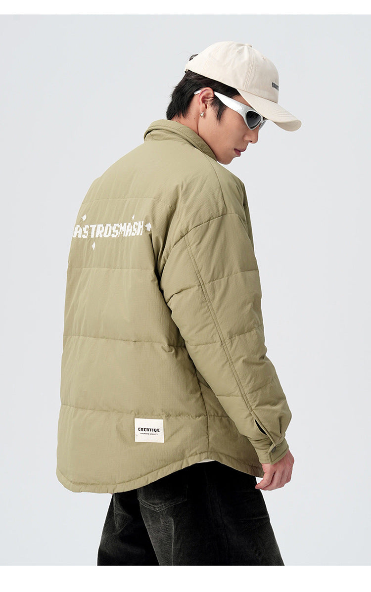 Side profile of model showing ASTROSMASH logo on back of olive puffer jacket with cream cap and dark pants