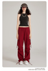 Model wearing black tank top and burgundy cargo pants with side pockets and drawstring details. Styled with cap, headphones and white sneakers