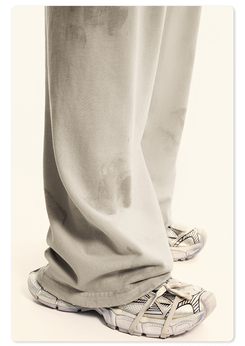 Close-up of black fabric with paint-splatter effect showing distressed Backstairs logo graphic in silver/gray print