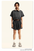 Model in dark gray crop top and shorts set with headphones, white socks and chunky sneakers on beige backdrop