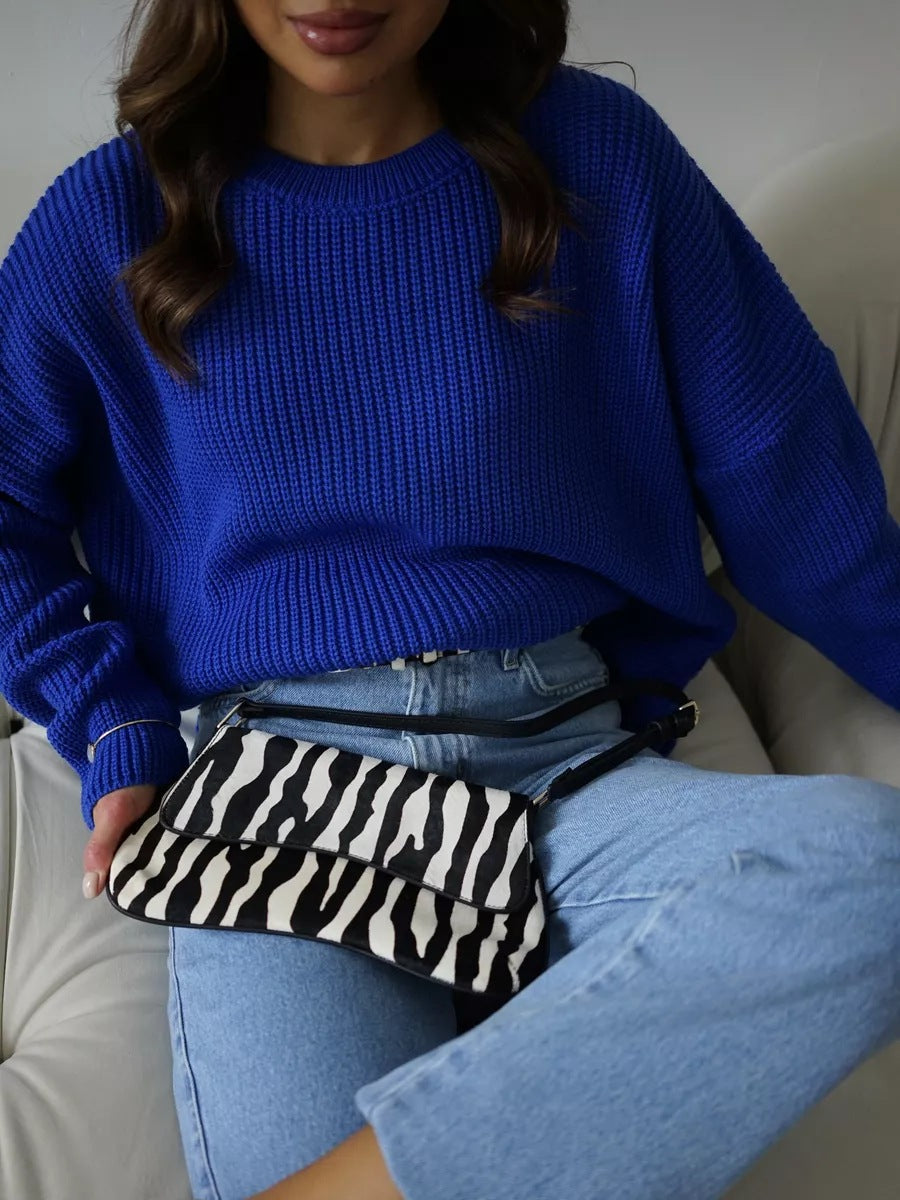 Royal blue sweater styled with zebra print handbag and light wash jeans, casual wear