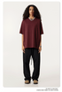Female model with curly hair wearing burgundy oversized t-shirt, black drawstring pants and beige mules, styled with silver chain necklace