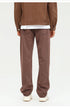 Brown wide-leg trousers with relaxed fit, styled with dark jacket and cream-colored sneakers