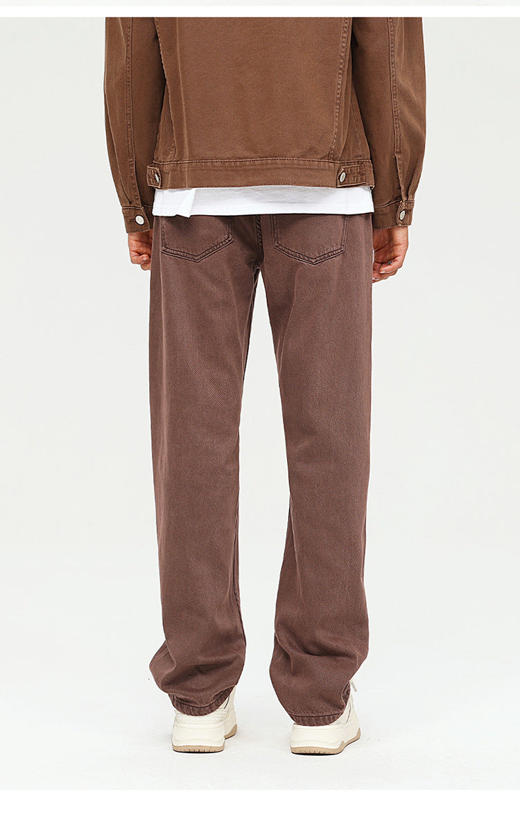 Brown wide-leg trousers with relaxed fit, styled with dark jacket and cream-colored sneakers