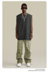 A model wearing oversized black muscle tank with silver chain necklace and lightning pendant, paired with olive-green cargo pants and white sneakers