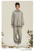 Woman in light gray hoodie and matching joggers with white headphones around neck against floral backdrop