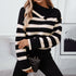A woman is standing with hand on quilted handbag wearing a black and white nautical striped sweater with decorative shoulder buttons