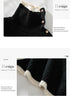 Detail view of the turtleneck collar with decorative gold buttons and contrast cream trim on black ribbed sweater, showing product features