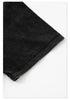 Close-up of black t-shirt fabric edge showing finished hem stitching and wash treatment