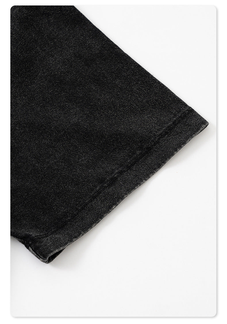 Close-up of black t-shirt fabric edge showing finished hem stitching and wash treatment