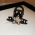 A black acrylic hair clip with a five-point star embellishment encrusted with sparkling rhinestones, displayed on a white jewelry tray.