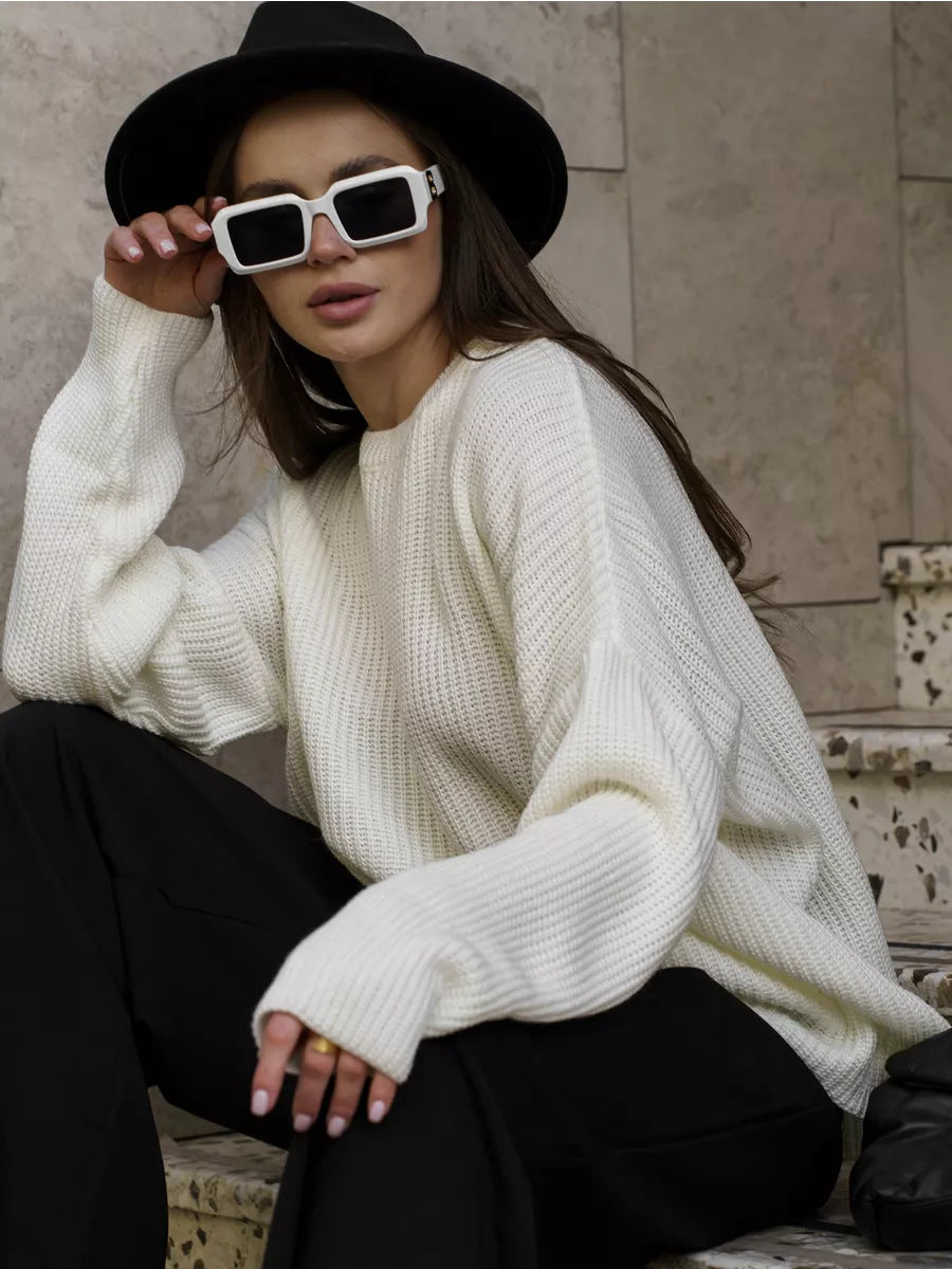 Woman in cream sweater with white rectangular sunglasses and black hat, urban setting