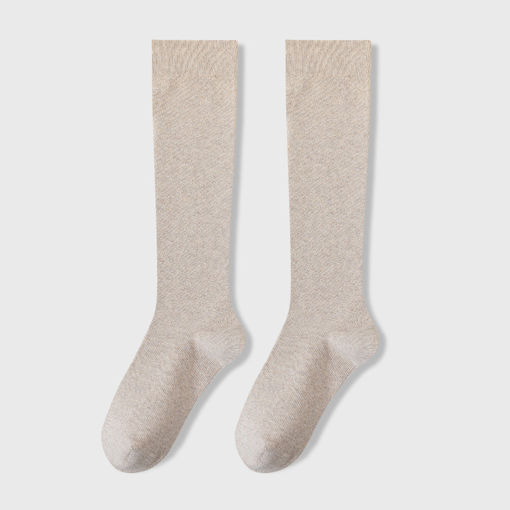 Pair of light beige knee-high socks displayed against white background showing soft textile texture