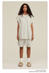 Model in white sleeveless top and matching shorts set with tan slides and silver chain necklace