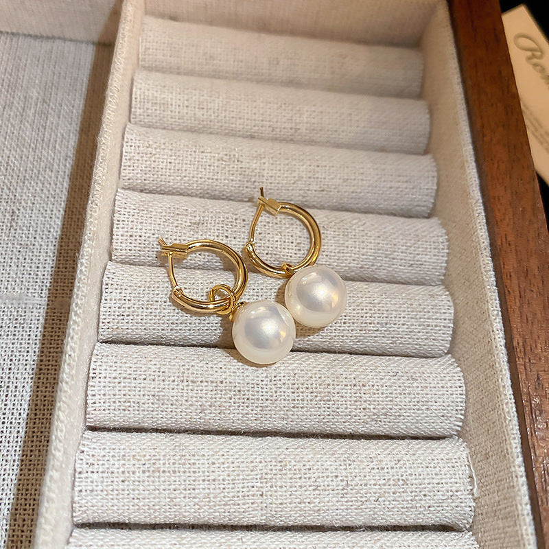 Gold hoop earrings with pearl drops, displayed in jewelry box