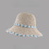 Beige woven straw hat with a wide brim, featuring blue floral embroidery along the brim and crown, displayed on a gray background.