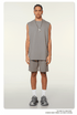 Model wearing gray matching set with oversized sleeveless top and shorts, silver pendant necklace and chunky white sneakers on neutral background