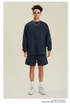 Man in navy sweatshirt and shorts set with white sunglasses, chain necklace and white sneakers