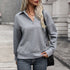 Close-up of blonde woman with wavy hair wearing gray textured pullover with collar detail and gold pendant necklace