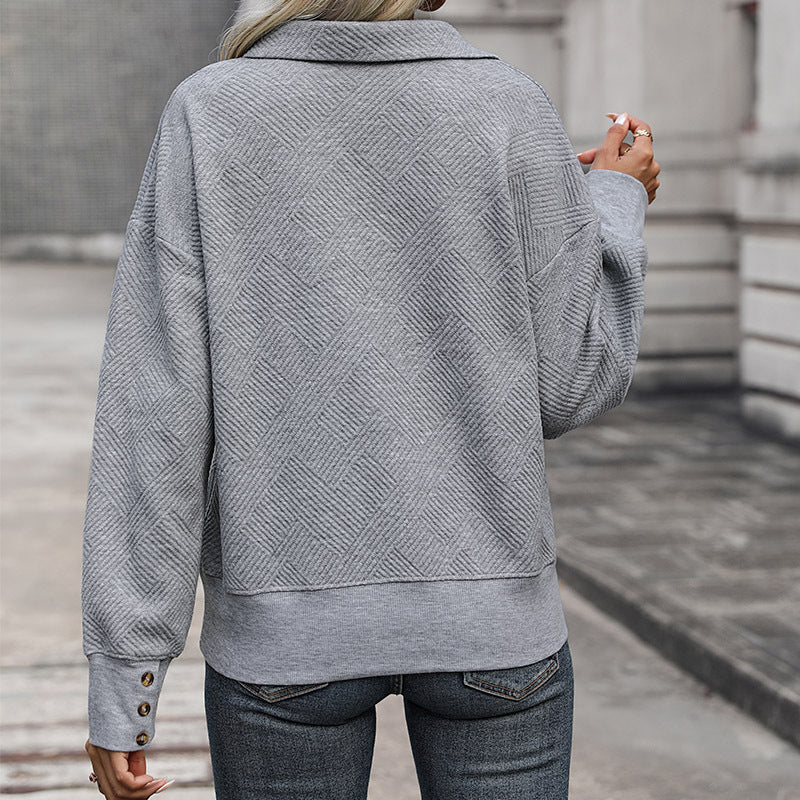 Back view of gray textured pullover showing basket weave pattern, decorative buttons at cuff, paired with dark jeans