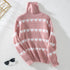 Pink heart pattern turtleneck sweater displayed flat against white background with gold geometric decor and sunglasses visible in corner