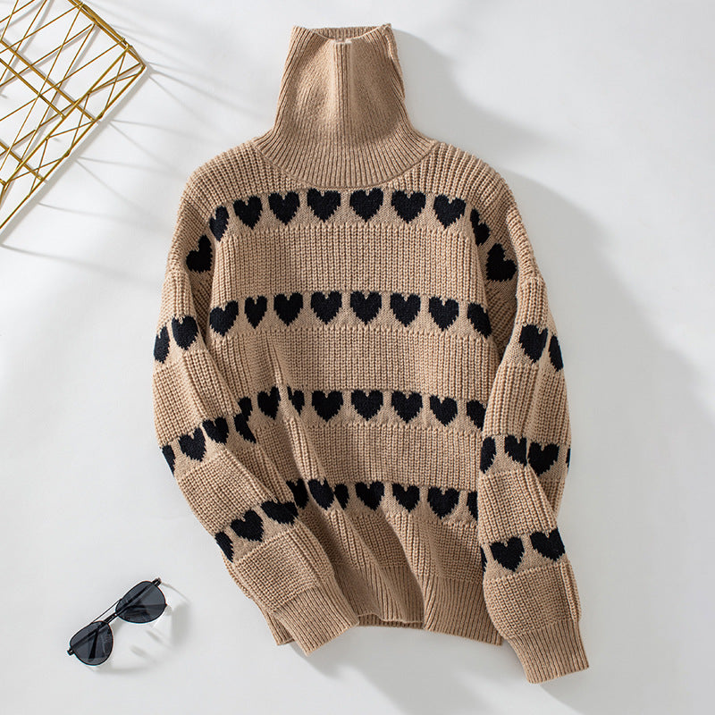 Beige turtleneck sweater with black heart pattern stripes displayed flat on white surface with gold decor element and sunglasses