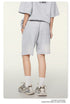 Back view of gray cotton sweatshorts with side pockets and relaxed fit, paired with vintage-style chunky sneakers