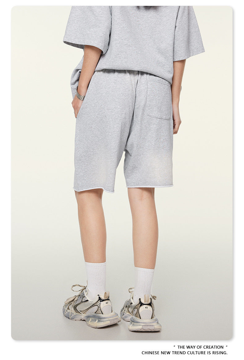 Back view of gray cotton sweatshorts with side pockets and relaxed fit, paired with vintage-style chunky sneakers