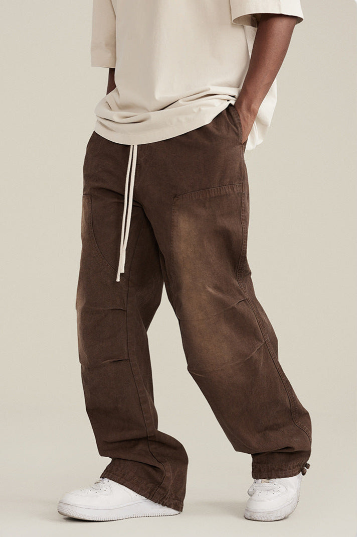 Close-up of brown wide-leg pants with drawstring, paired with white t-shirt and sneakers