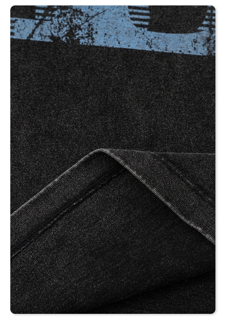 Fabric detail of black t-shirt showing blue print texture and folded material against white background