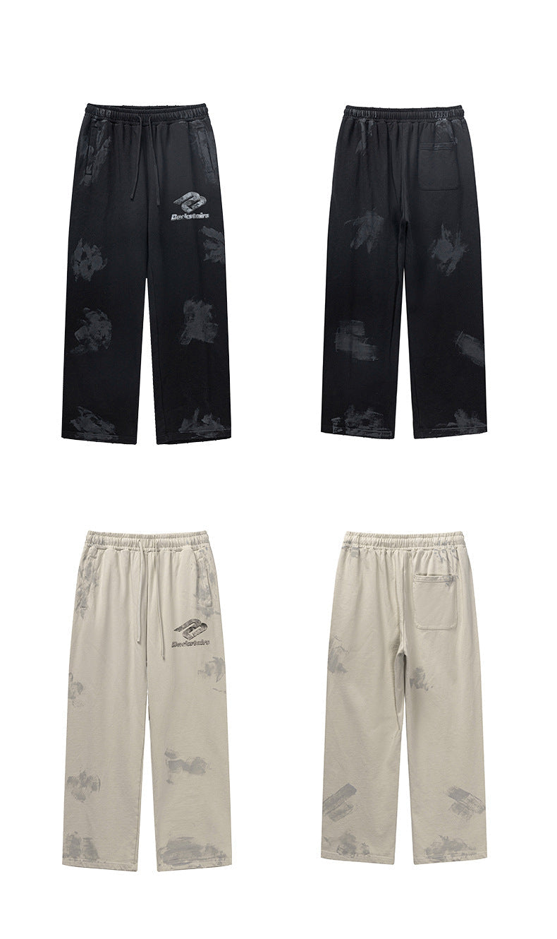 Product lineup showing black and cream Backstairs sweatpants, front and back views with distressed paint-splatter patterns