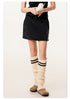 Model wearing black mini skirt with cream striped leg warmers, displaying casual styling with vintage phone prop