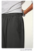 Close-up of dark pants waistband with pocket and wrist with silver watch against white background