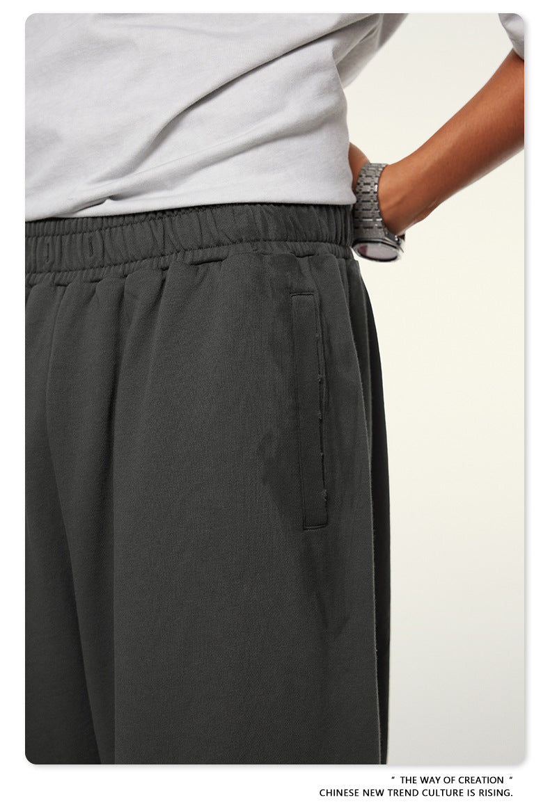 Close-up of dark pants waistband with pocket and wrist with silver watch against white background