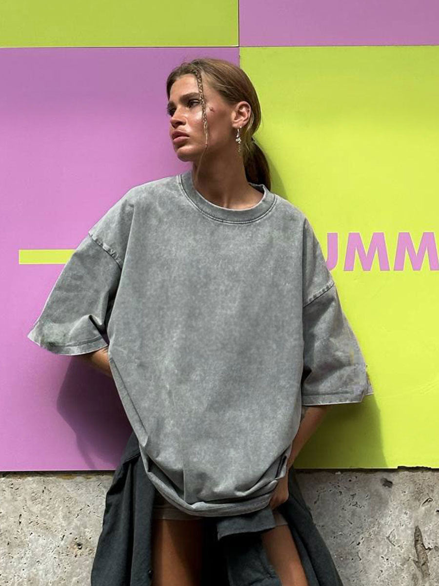 Person wearing a gray oversized sweatshirt against a colorful geometric background