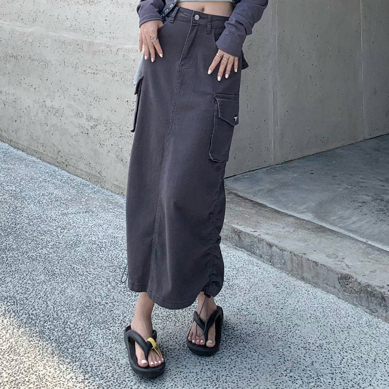 Close-up of charcoal cargo maxi skirt showing pocket placement and drawstring hem, paired with platform sandals