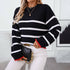 Black and white striped knitwear styled with quilted black handbag, gold chain accessories and white pants for modern winter outfit