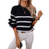 Casual cold weather outfit combining striped black sweater, gold jewelry, and white pants, showcasing minimalist winter fashion style