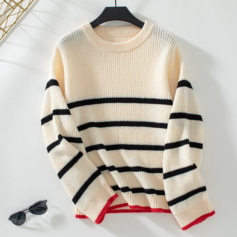 Cream colored striped knit sweater with black horizontal stripes and red trim displayed on hanger against white background with sunglasses