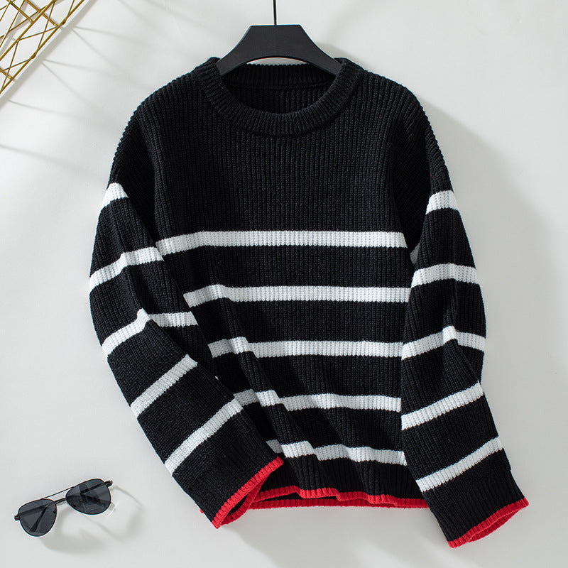 Black ribbed sweater with white stripe pattern and red cuff detail hanging on display, styled with aviator sunglasses for winter fashion