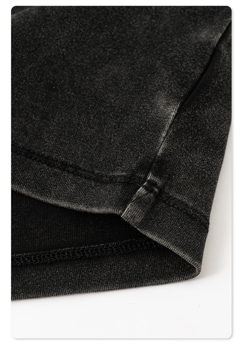 Close-up of the folded sleeve hem on a black washed cropped T-shirt, showing precise stitching and fabric texture