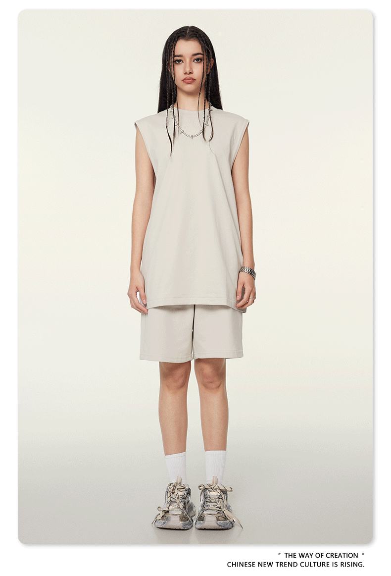Model wearing cream/beige matching set with sleeveless top and shorts, white socks and chunky sneakers on neutral background