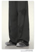 Close-up of dark wide-leg pants hem with gray footwear against white background