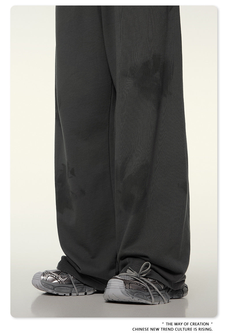 Close-up of dark wide-leg pants hem with gray footwear against white background