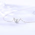 Close-up product shot of silver W pendant necklace with crystal accents on white background