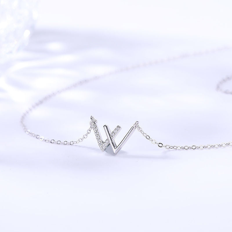 Close-up product shot of silver W pendant necklace with crystal accents on white background
